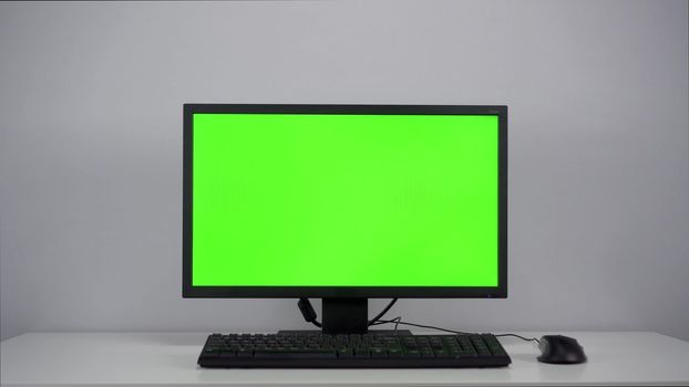 Green screen on a computer monitor in the office. Chroma key on pc. 4k