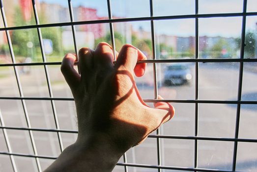 Man in prison hand holding a steel cage prison bars. criminal criminal is locked in prison. The hand of a detained man in a police car.
