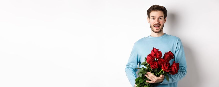 Romantic boyfriend bring beautiful bouquet of red roses on valentines day, having date with girlfriend, saying I love you, standing passionate on white background.