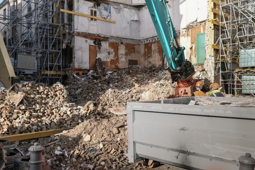 Ruined house. An excavator destroys a house with a bucket.