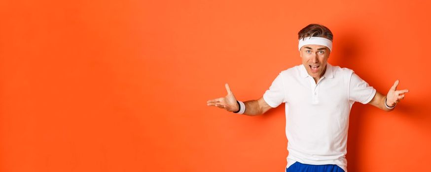 Concept of workout, sports and lifestyle. Portrait of confused middle-aged sportsman complaining, spread hands sideways and looking puzzled, cant understand something, orange background.