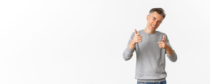 Portrait of handsome and confident middle-aged man, showing thumbs-up and smiling satisfied, approve and like something good, standing over white background.