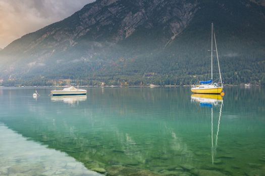 Sailboats on Achensee lake near Innsbruck at peaceful misty dawn, Tyrol alps, Austria
