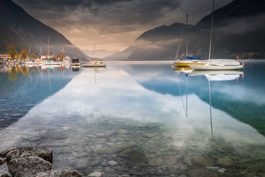 Sailboats on Achensee lake near Innsbruck at peaceful misty dawn, Tyrol alps, Austria
