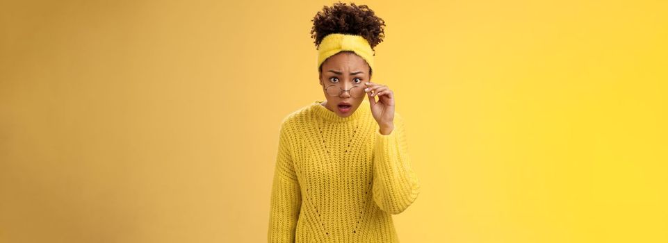 Shocked amazed african-american female student drop jaw gasping concerned confused take-off glasses bending forward reassure see truth, standing impressed speechless, yellow background.