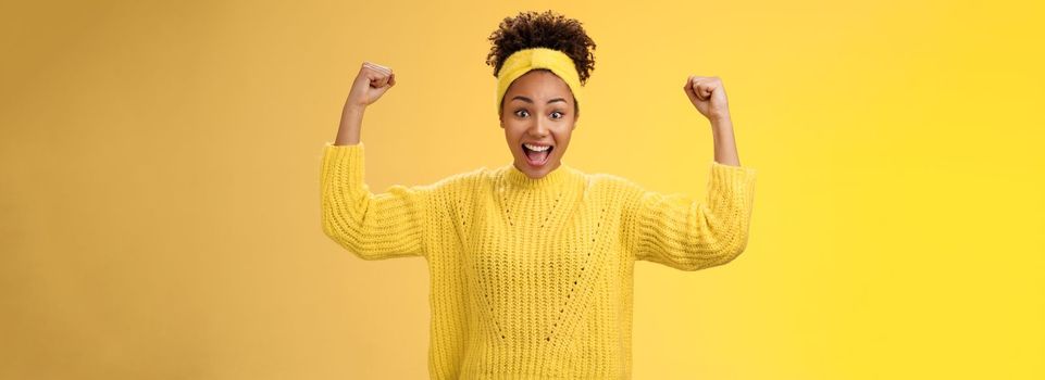 Proud impressed charming girlfriend encourage girlfriend win first place happy for friend rase fists celebration triumph gesture smiling broadly congratulation good work win, yellow background.