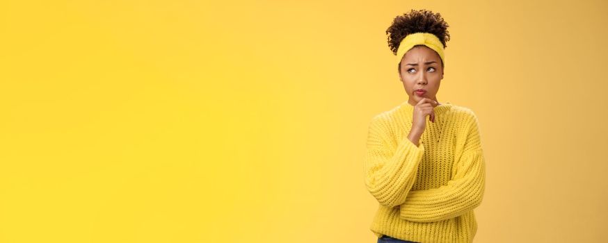 Unsure hesitant worried cute african-american girl face tough decision look up thoughtful make plan thinking how act right touch chin, make assumption standing concerned yellow background.