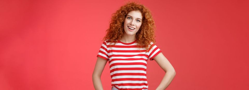 How hanging. Friendly carefree redhead curly-haired relaxed outgoing woman speaking casually entertained happy mood hold hands jeans pockets tilt head intrigued, curiously look camera.