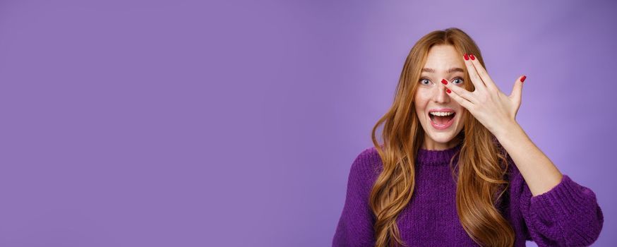 Waist-up shot of enthusiastic and charismatic cute funny redhead woman in purple sweater with cool nails showing peeking through holes in fingers and smiling optimistic and excited, looking surprised.