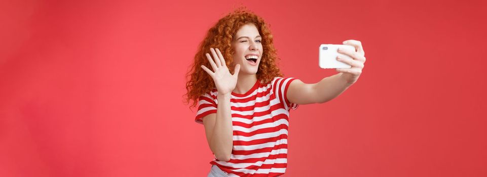 Lifestyle. Cheerful friendly energized good-looking redhead curly-haired female send hello waving palm smiling broadly blogger record life stream talking fans grinning taking selfie summer holiday trip.