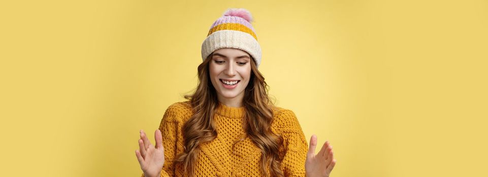 Attractive tender girl retelling friends what got b-day present describing large present box smiling happily look down shaping big thing talking joyfully excited, standing happy yellow background.