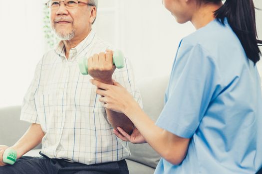 Contented senior patient doing physical therapy with the help of his caregiver. Senior physical therapy, physiotherapy treatment, nursing home for the elderly