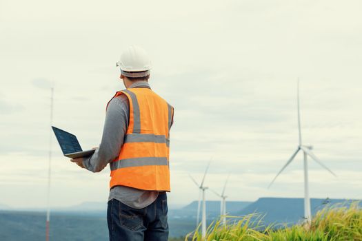 Engineer working on a wind farm atop a hill or mountain in the rural. Progressive ideal for the future production of renewable, sustainable energy. Energy generation from wind turbine.