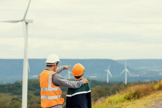 Engineer with his son on a wind farm atop a hill or mountain in the rural. Progressive ideal for the future production of renewable, sustainable energy. Energy generation from wind turbine.