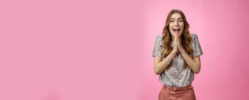 Excited attractive girlfriend eager start pack ready travel abroad win tickets press palms together happily thrilled looking amused feeling happiness standing pink background glamour outfit.