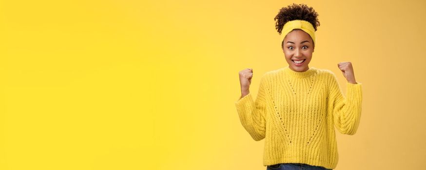Surprised cute tender african-american girl cannot believe win prize lottery clench fists triumphing smiling broadly widen eyes impressed astonished celebrating success, victory yellow background.