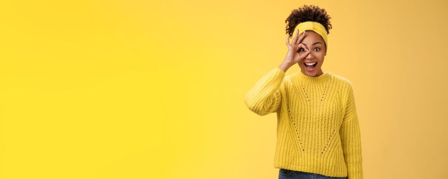 Dreamy impressed excited african-american female university student speechless smiling drop jaw look awesome future show okay ok excellent gesture on eye look through dreamy, yellow background.