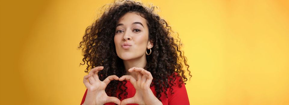 Close-up shot of romantic and tender young girlfriend with curly hair folding lips in kiss or mwah showing heart gesture, expressing love and romance, confessing in admiration or sympathy. Relationship, holidays and facial expressions concept
