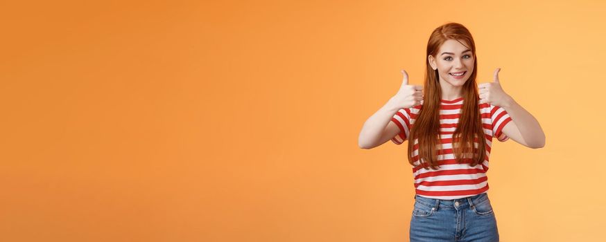 Good work, keep going. Girl encourage friend, say well done, show satisfactory sign, thumbs-up and smiling pleased, agree, approve nice choice, accept point view, stand orange background.