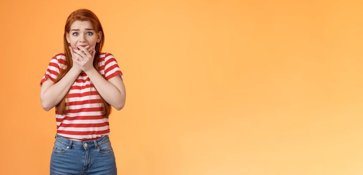 Scared speechless innocent female victim losing speech, press hands mouth shocked terrified stare camera frightened, trembling from fear, see someone commiting crime, insecure orange background.