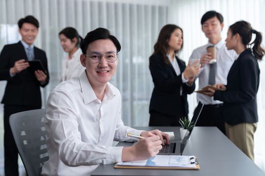 Portrait of focus young successful confident male manager, executive wearing business wear in harmony office arm crossed with blurred meeting background of colleagues, office worker.