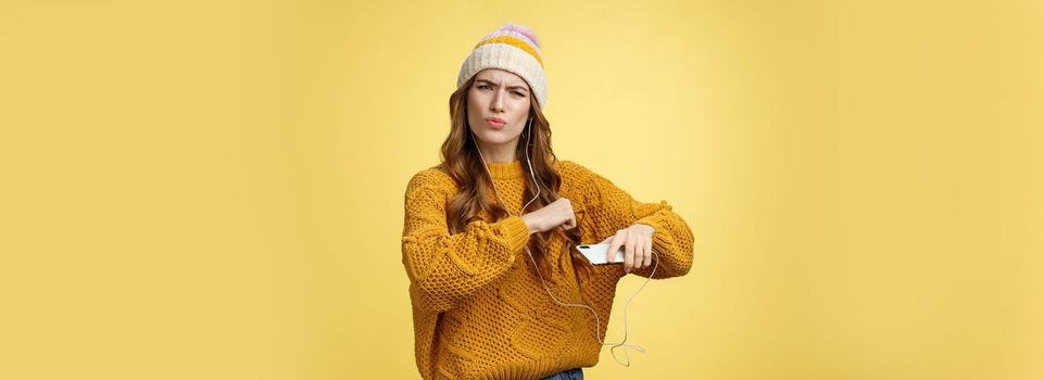 Shake your body. Portrait cool amused good-looking stylish girlfriend listen music via wired earphones dancing moving hands rhythm cool song holding smartphone folding lips frowning satisfied.