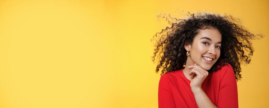 Romance, women and beauty concept. Portrait of tender and gentle pretty woman with curly hair flying in air as she turning head and smiling sensually, flirting with camera touching chin.