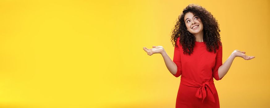 Girl feeling clueless and silly, being unbothered with anything, shrugging dreamy and indifferent, smiling carefree as looking dreamy at upper right corner, spread hands sideways in uncertain gesture.