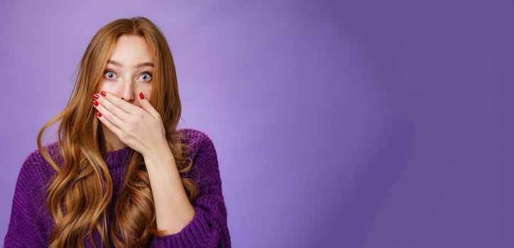 Lifestyle. Impressed speechless cute ginger girl hearing stunning gossip covering mouth form amazement and shook raising eyebrows wondered as reacting to unexpected revelation or rumor over purple background.