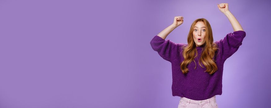 Excited and thrilled woman reacting to unexpected goal raising hands in wave gesture folding lips inhaling breath to scream yes and wow being impressed, triumphing from success and good news.