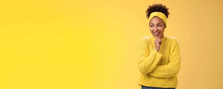 Impressed excited surprised happy attractive african-american curly-haired girl headband sweater giggling amazed look left touching chin thoughtful laughing funny scene, standing yellow background.