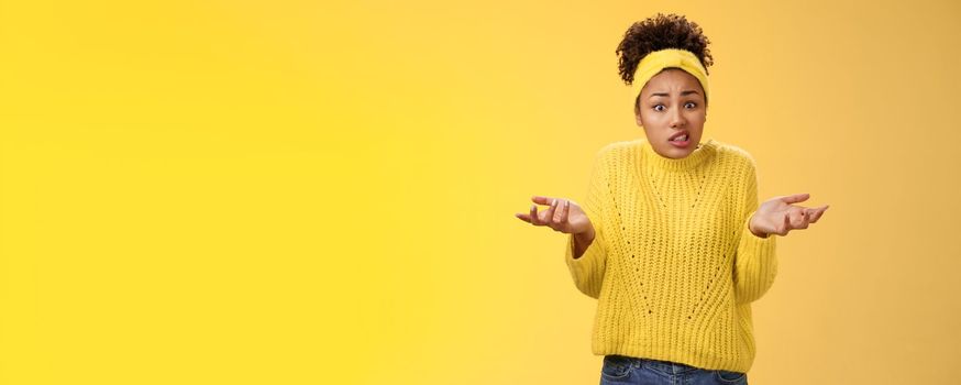 Confused awkward cute female employee messed-up papers lost paperwork shrugging raise hands uncertain say oops cringing uncomfortable standing clueless no idea what happening, yellow background.