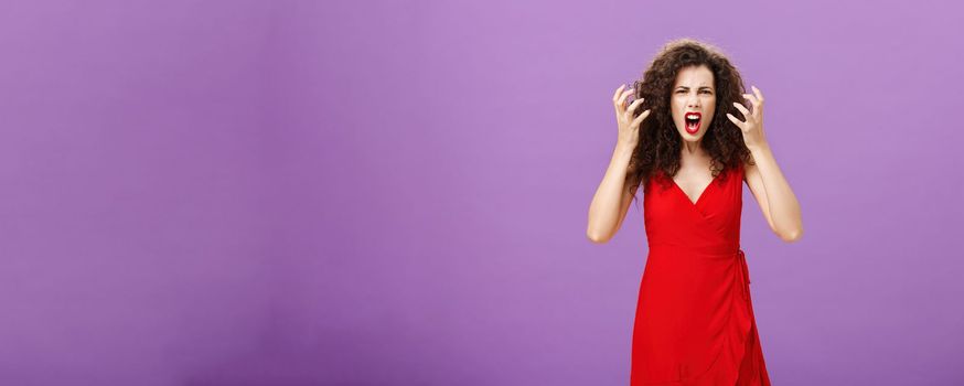 Woman getting annoyed and pissed employees spoiling her perfomance. Portrait of outraged furious female musician in red evening dress raising clenched fists grimacing and yelling angry. Copy space