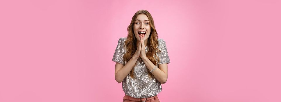 Excited attractive girlfriend eager start pack ready travel abroad win tickets press palms together happily thrilled looking amused feeling happiness standing pink background glamour outfit.