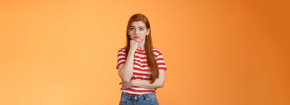Upset redhead woman losing lottery feel uneasy distressed, look up regret loss, lean on fist pulling sad face, standing lonely unhappy orange background thinking, taking hard decision.