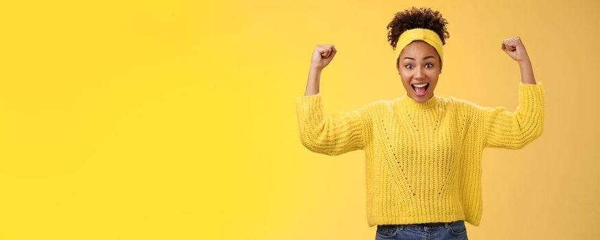 Proud impressed charming girlfriend encourage girlfriend win first place happy for friend rase fists celebration triumph gesture smiling broadly congratulation good work win, yellow background.