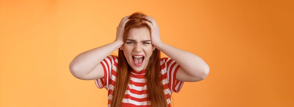 Pissed fed up redhead female teenager annoyed, break down, grab head yelling hateful displeased, depressed, upset failure, stand angry disappointed, panic, shouting aggressive orange background.