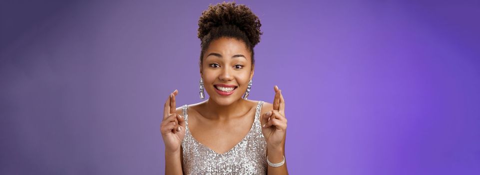 Cheerful optimistic charming african american girlfriend. supporting friend make wish wanna win first prize cross fingers luck smiling broadly wear glittering silver dress anticipating good fortune.