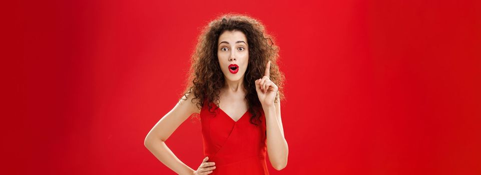 Got excellent idea listen. Portrait of creative friendly and smart attractive caucasian woman in elegant red dress with evening make-up gasping adding suggestion raising index finger in eureka gesture.