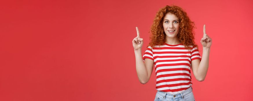 Lifestyle. Excited good-looking cheeky redhead ginger girl curly natural hair pointing raised index fingers up smiling impressed thrilled advising store directing promo advertising awesome haircare product.