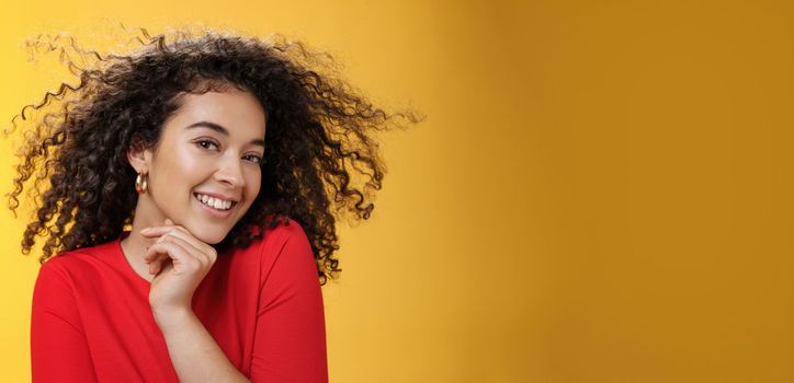 Romance, women and beauty concept. Portrait of tender and gentle pretty woman with curly hair flying in air as she turning head and smiling sensually, flirting with camera touching chin.