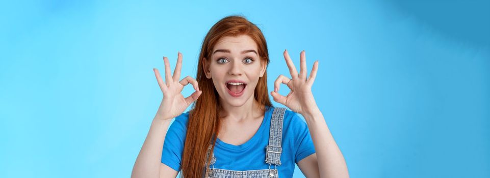 Excellent choice. Redhead female friend approve awesome idea, support accept good purshace, show okay ok confirmation gesture, smiling judging, give positive feedback, stand satisfied blue background.