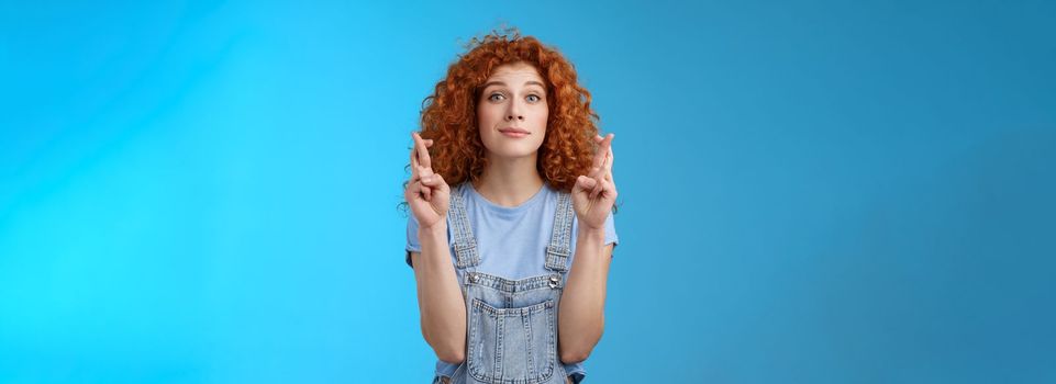 Lifestyle. Hopeful relaxed optimistic cute european redhead curly girl smiling faithfully awaiting good results believe wish come true cross fingers good luck grin anticipating important news dream fulfill.