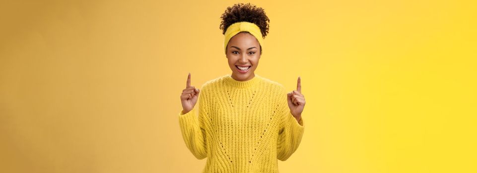 Excited charming young african-american girlfriend afro hairstyle in sweater headband pointing up index fingers smiling giggling asking buy boyfriend awesome cosmetics b-day present.