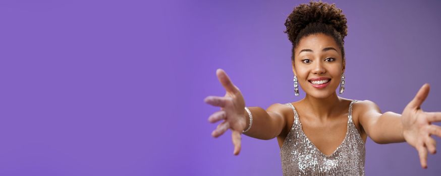 Close-up charming touched tender wealthy african-american. woman in silver fashionable dress extend arms towards camera give warm welcome hug smiling delighted wanna cuddle hold in hands.