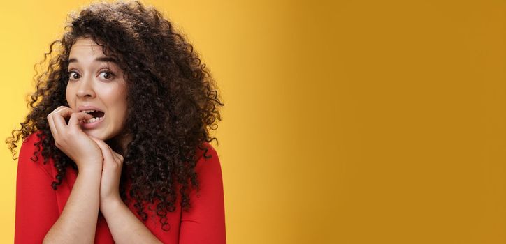 Lifestyle. Portrait of worried woman biting fingernails as feeling insecure and scared of boyfriend find out she spent all money on credit card standing silly acting like unaware looking nervously at camera.