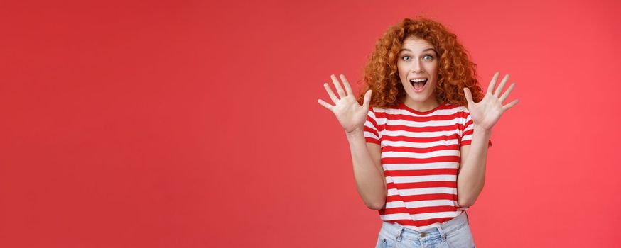 Extremely wonderful news she excited. Thrilled emotive gorgeous redhead woman scream amazed awesome surprise raise hands waving impressed open mouth stare charmed fascinated red background.