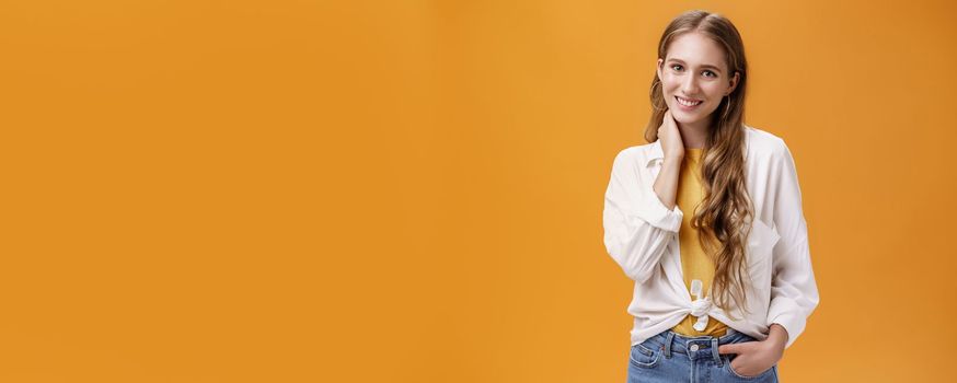 Girl dressing up for success. Charming feminine and stylish young female with wavy natural hairstyle touching neck timid and shy smiling cheerfully at camera wearing large earrings and blouse.