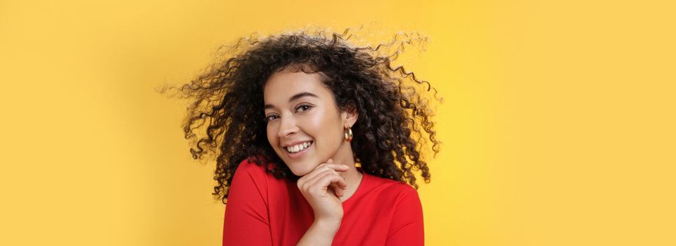 Romance, women and beauty concept. Portrait of tender and gentle pretty woman with curly hair flying in air as she turning head and smiling sensually, flirting with camera touching chin.