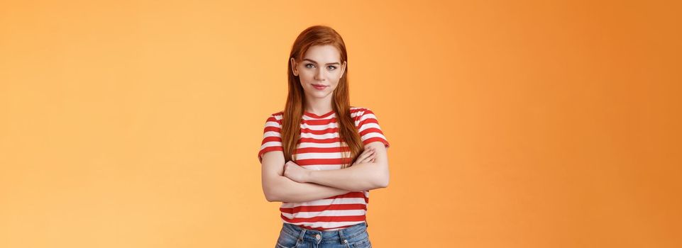 Go on try me. Confident cool redhead daring woman cross arms professional pose, smiling determined motivated win, look assertive and assured own powers, stand orange background. Copy space